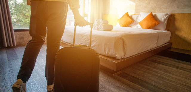 Voyage solo : bagage devant un lit d'hôtel